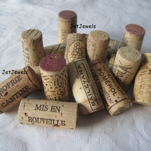 May include: A collection of used wine corks with various printed labels and markings. The corks are cylindrical, made of natural cork material, and display text such as "PROPRIE CANTINE" and "MIS EN BOUTEILLE". Some corks have a reddish-purple top.