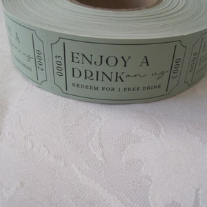 Puede incluir: Un rollo de tickets de papel verde con texto negro que dice "Disfruta de una bebida por nuestra cuenta. Canjea por 1 bebida gratis." Los tickets est&aacute;n numerados 00003.