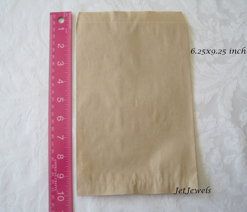 May include: A brown paper bag with a 6.25 x 9.25 inch measurement. The bag is folded and has a crease down the middle.
