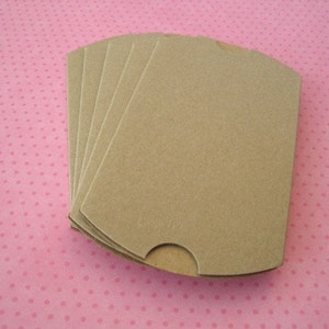 May include: A stack of six brown paper favour boxes with scalloped edges. The boxes are folded flat and ready to be assembled.