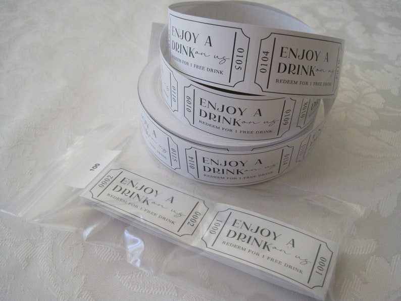 Puede incluir: Un rollo de tickets de bebida de papel blanco con texto negro que dice "Disfruta de una bebida por nuestra cuenta. Canjea por 1 bebida gratis".