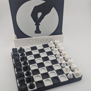 May include: A black and white chess set with a matching black and white display stand. The stand features a hand holding a chess piece in a white circle. The word "Chess" is printed on the stand. The chess board is black and white.