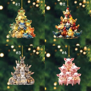 May include: Four Christmas tree ornaments. Each ornament features a different animal stacked in a tree shape. The animals include frogs, chickens, rabbits, and pigs. Each ornament has a gold string for hanging and is decorated with small lights.