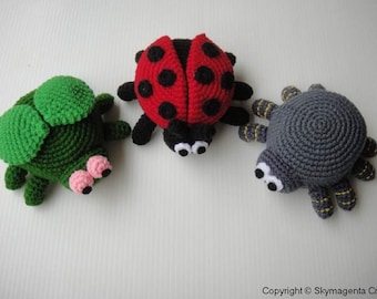 May include: Three crocheted stuffed animals: a green ladybug, a red ladybug with black spots, and a gray spider with yellow stripes.