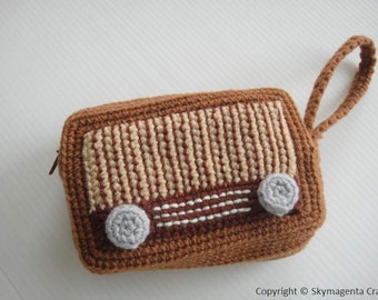 Op de afbeelding: Een bruine gehaakte tas in de vorm van een vintage radio met een bruine band. De radio heeft een wit en bruin gestreept ontwerp en twee grijze knoppen.