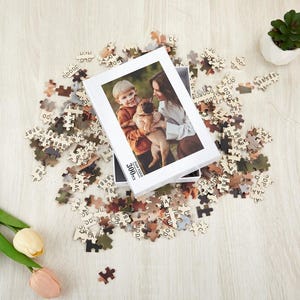May include: A 300 piece jigsaw puzzle featuring a photo of a woman and a child with a dog. The puzzle box is white with black text and a photo of the puzzle image.