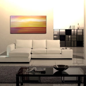 May include: A white sectional sofa with a low coffee table in front of it. The sofa is in a modern living room with a large abstract painting on the wall behind it.