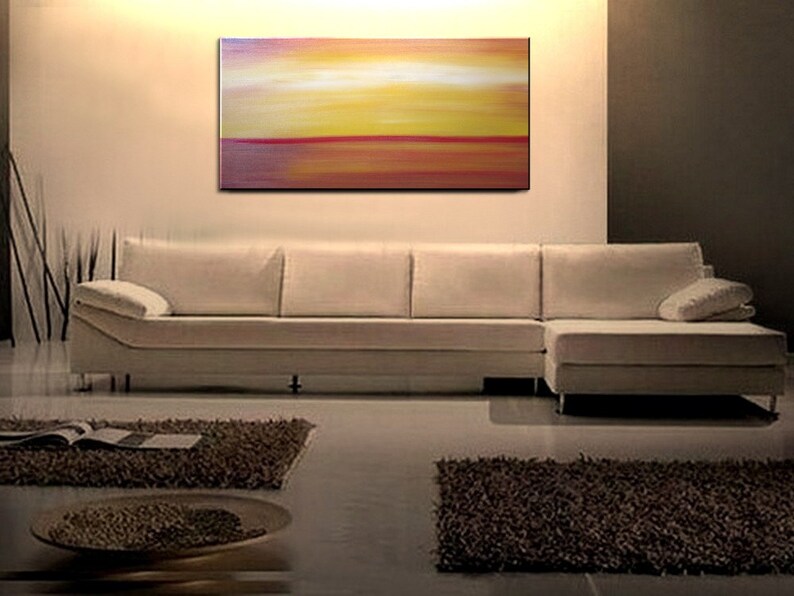 May include: Abstract painting with horizontal stripes of red, orange, yellow, and white. The painting is on a white wall above a white sectional sofa.