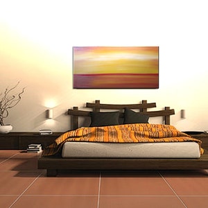 May include: A bedroom with a wooden bed frame and a colorful abstract painting above the headboard. The bed is made with a white duvet and a patterned orange throw blanket. The room has a light brown tiled floor and a wooden side table with a plant on it.