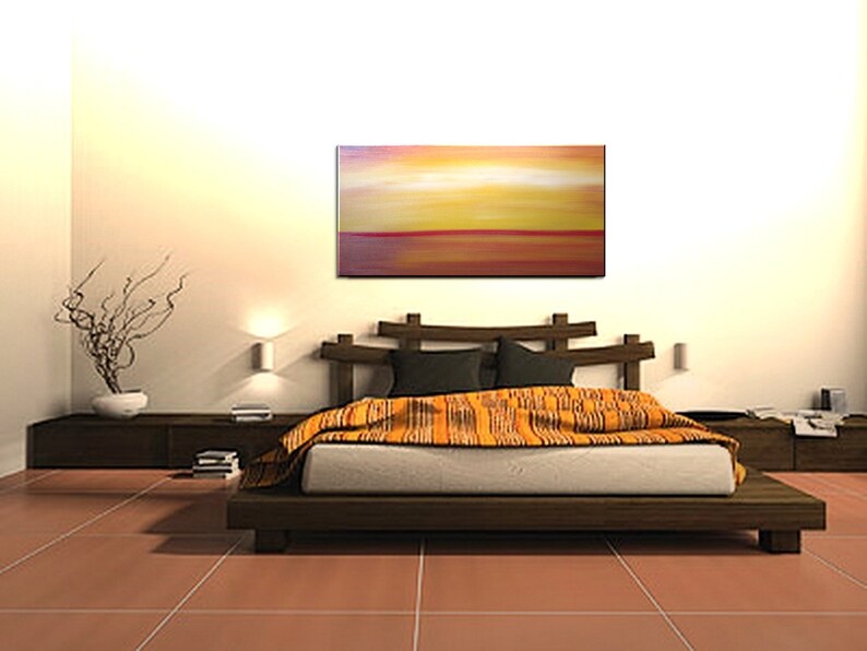 May include: A bedroom with a wooden bed frame and a colorful abstract painting above the headboard. The bed is made with a white duvet and a patterned orange throw blanket. The room has a light brown tiled floor and a wooden side table with a plant on it.