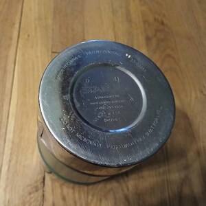 Puede incluir: La base circular de un vaso de metal plateado con texto en relieve que dice Stanley, A Brand of PMI, Made in China, Patent Pending, 20-00085, 14 oz / 0.4 L, Do Not Microwave, Hand Wash Only y Built for Life.