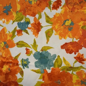 May include: A white fabric featuring a dense floral pattern with large, painterly flowers in shades of bright orange, deep red, and muted teal. The design includes green leaves and stems interspersed among the blossoms, creating a continuous botanical print across the surface of the textile material.