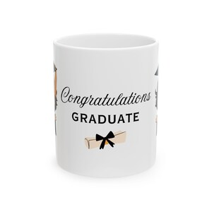 May include: White ceramic coffee mug with a black and white illustration of a graduation cap, a diploma, and the text "Congratulations GRADUATE".
