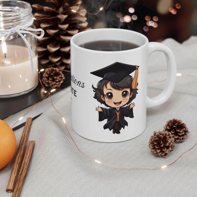 May include: White ceramic coffee mug with a black and yellow cartoon graduate wearing a cap and gown. The mug has the text "Congratulations Graduate" on it.