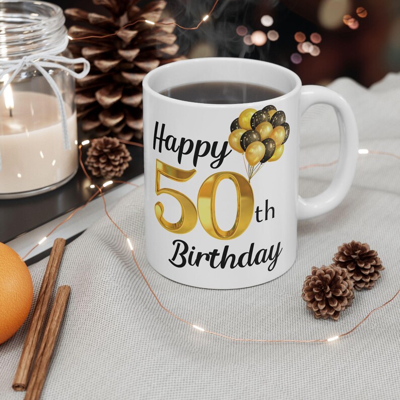 May include: White ceramic mug with a black and gold design. The mug says "Happy 50th Birthday" with gold balloons.