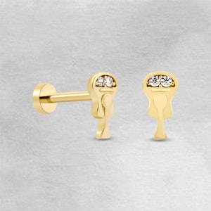 Peut inclure: Boucle d'oreille en or en forme de clé avec deux petites pierres précieuses claires. La boucle d'oreille est conçue pour un piercing au cartilage.