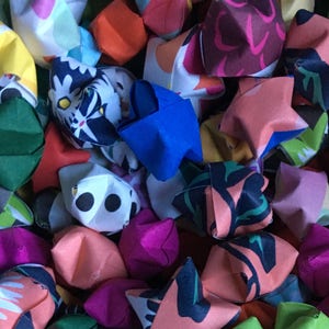 May include: A collection of colorful origami lucky stars with various patterns and designs. The stars are made of paper and are folded into a five-pointed star shape.