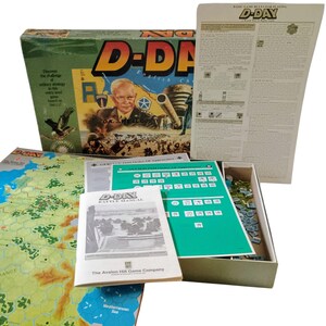 May include: A vintage D-Day board game, featuring a box with the title in yellow lettering. The box art shows a portrait, soldiers, and a tank. The game includes instructions, a map, and game pieces, all in a box.