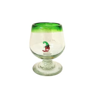 May include: A clear glass goblet with a green rim and a small, colourful chilli pepper design inside. The goblet has a rounded bowl and a short stem, ideal for serving beverages.