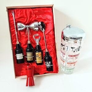 May include: A vintage cocktail set with a red satin lining. The set includes a cocktail shaker, a double jigger, and bar tools with bottle-shaped handles. The shaker has a silver lid and a glass body with cocktail recipes.