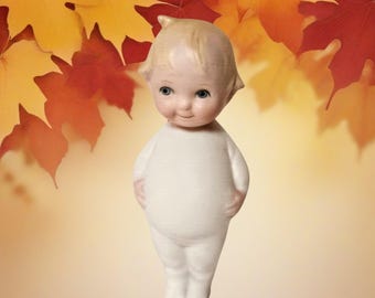 Poupée Kewpie de 12,7 cm en porcelaine biscuit mate, fabriquée en Allemagne. Cheveux coiffés en chignon, bras reposant sur le ventre proéminent, avec support en plastique.