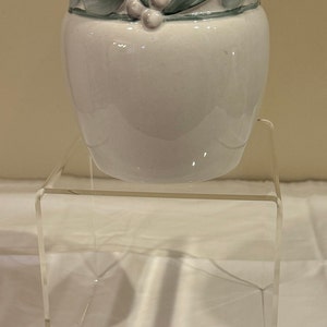 May include: White ceramic vase with a green and white floral design around the top.