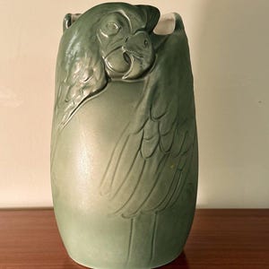 May include: A green ceramic vase shaped like a bird with detailed wings and a bird's head.