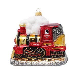 May include: A red and gold Christmas train ornament with a white cloud of snow on top. The ornament has black wheels and a gold hanging loop. The train is sitting on a silver base.