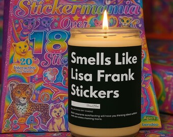 Op de afbeelding: Een brandende kaars in een glazen pot met een zwart etiket met de tekst "Smells Like Lisa Frank Stickers". Op de achtergrond staat een kleurrijk Lisa Frank stickerboek. De kaars is 255 g.