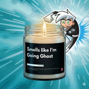 Puede incluir: Una vela encendida en un tarro de cristal con una etiqueta negra que dice "Smells like I'm Going Ghost". La vela es de 255g. Un personaje de dibujos animados está en el fondo con un fondo azul y blanco.