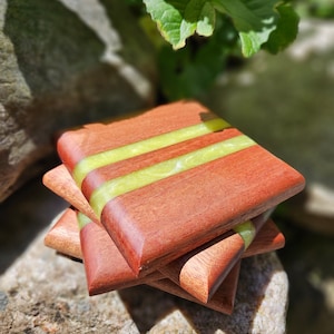 May include: Four wooden coasters with a green resin inlay. The coasters are stacked on top of each other.