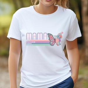May include: White t-shirt with the word "MAMA" in a retro font, a butterfly, and floral accents. Below the word "MAMA" are the words "HARDWORKING, SELFLESS, PROTECTIVE" in a pastel color scheme.