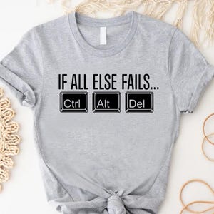 May include: A light gray t-shirt with the text "IF ALL ELSE FAILS..." above the Ctrl, Alt, and Del keys. The shirt is knotted at the waist.