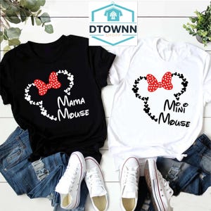 K&ouml;nnte beinhalten: Zwei schwarze und wei&szlig;e T-Shirts mit einer roten Schleife und Mickey-Maus-K&ouml;pfen. Das schwarze Shirt sagt "Mama Mouse" und das wei&szlig;e Shirt sagt "Mini Mouse".