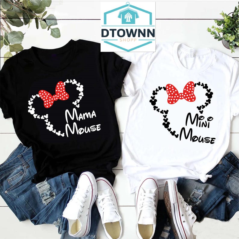 K&ouml;nnte beinhalten: Zwei schwarze und wei&szlig;e T-Shirts mit einer roten Schleife und Mickey-Maus-K&ouml;pfen. Das schwarze Shirt sagt "Mama Mouse" und das wei&szlig;e Shirt sagt "Mini Mouse".