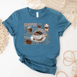 May include: A teal blue t-shirt featuring a coffee cup and coffee beans graphic. The graphic includes the word "Coffee" repeated multiple times.