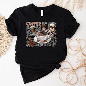 May include: Black t-shirt featuring a graphic design of coffee cups, coffee beans, and the word "Coffee" repeated in various fonts and sizes.