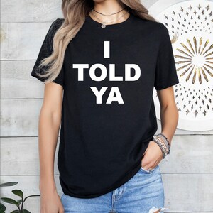 May include: Black t-shirt with white text that reads "I TOLD YA".
