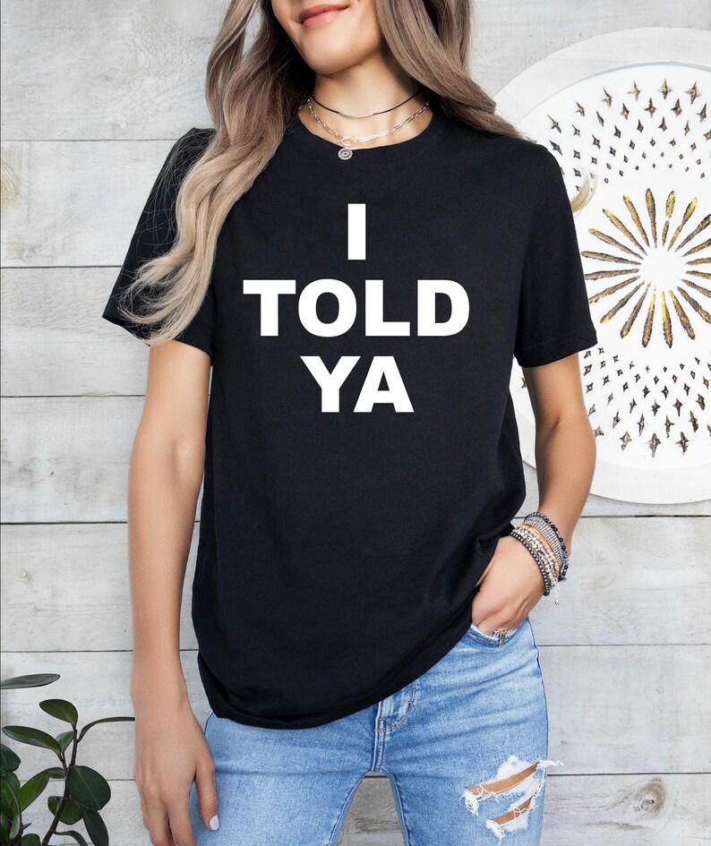 May include: Black t-shirt with white text that reads "I TOLD YA".