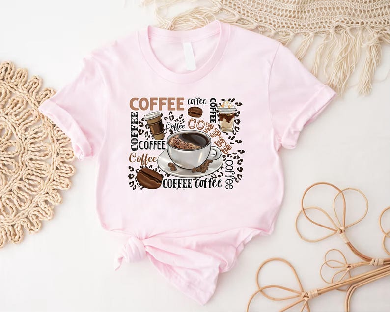 May include: Pink t-shirt featuring a coffee cup, coffee beans, and the word "Coffee" repeated several times.