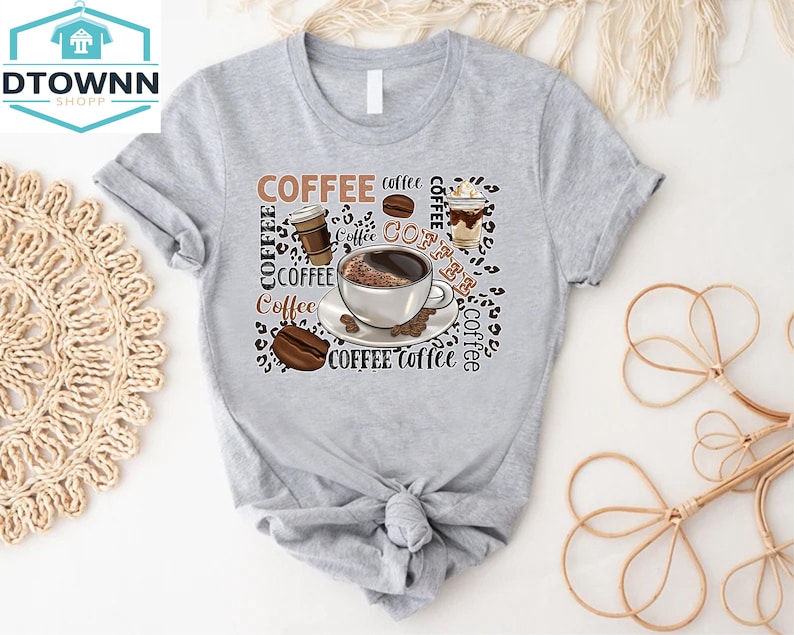 May include: Grey t-shirt with a coffee cup and coffee beans design. The text "COFFEE" is repeated multiple times on the shirt.