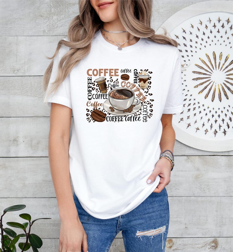 May include: White t-shirt with a brown and white graphic design featuring a coffee cup, coffee beans, and the word "COFFEE" repeated multiple times.