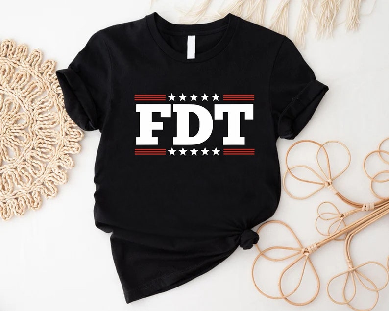 May include: Black t-shirt with white text that says "FDT" in bold letters. The text is surrounded by red stripes and white stars.