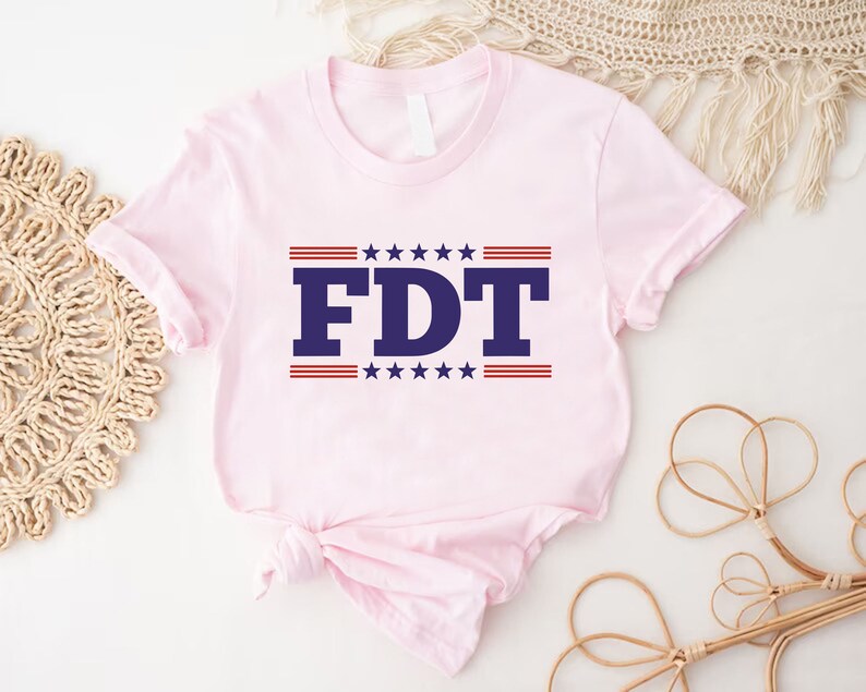 May include: Pink t-shirt with a blue and red graphic that says "FDT" with stars and stripes.