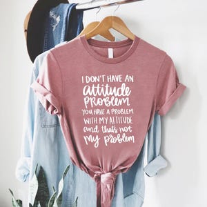 K&ouml;nnte beinhalten: Staubrosafarbenes T-Shirt mit wei&szlig;em Text: "I DON'T HAVE AN attitude PROBLEM YOU HAVE A PROBLEM WITH MY ATTITUDE and that's not my problem". Das T-Shirt ist unten geknotet.