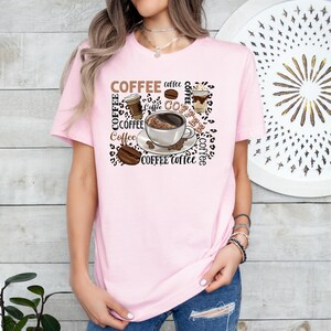May include: A pink t-shirt featuring a graphic design of coffee cups, coffee beans, and the word "COFFEE" repeated in various sizes and styles.