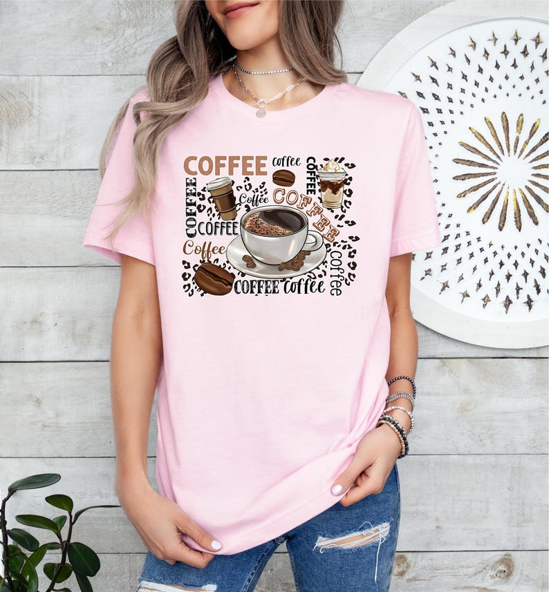 May include: A pink t-shirt featuring a graphic design of coffee cups, coffee beans, and the word "COFFEE" repeated in various sizes and styles.