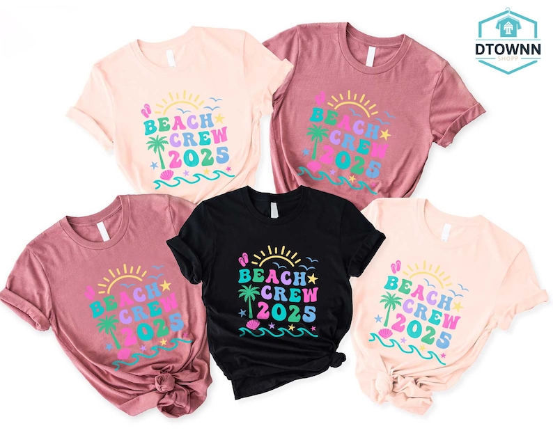 Puede incluir: Cinco camisetas de manga corta en varios colores: rosa claro, malva y negro. Cada camiseta presenta el texto "BEACH CREW 2025" en un dise&ntilde;o colorido con un sol, una palmera y olas. Las camisetas est&aacute;n bien dispuestas.