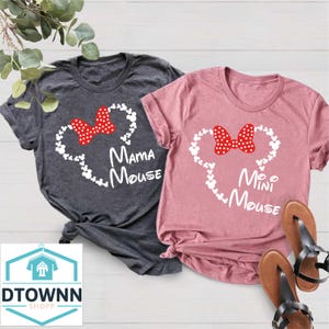 K&ouml;nnte beinhalten: Zwei T-Shirts mit einer wei&szlig;en Umrandung von Mickey Mouse Ohren und einer roten Schleife. Das gr&ouml;&szlig;ere Shirt sagt "Mama Mouse" und das kleinere Shirt sagt "Mini Mouse".