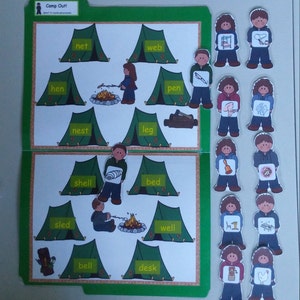 May include: A learning tool with the title "Camp Out!" featuring illustrations of tents, campfires, and related objects. Each tent has a word printed on it, such as "net" and "web." Small paper cutouts of children holding objects are also included.